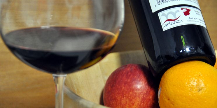 Botella de vino Arlanza, copa con vino y fruta.